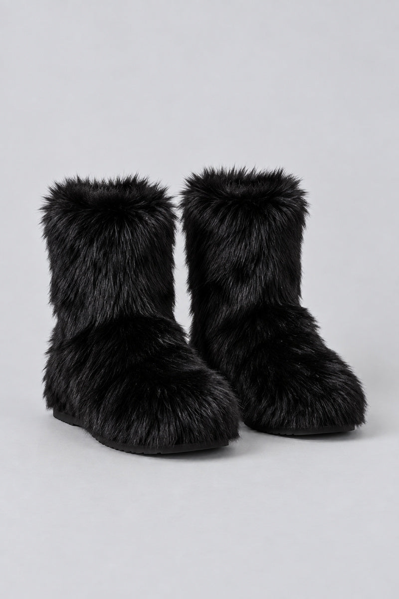 Bottes en moumoute noires, paire seule sur fond studio gris clair.