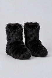 Bottes en moumoute noires, paire seule sur fond studio gris clair.