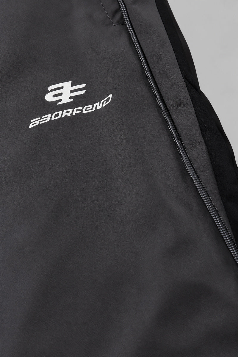 Jogging Y2K édition 'Shadow Sport', détail du logo, sur fond studio gris clair.