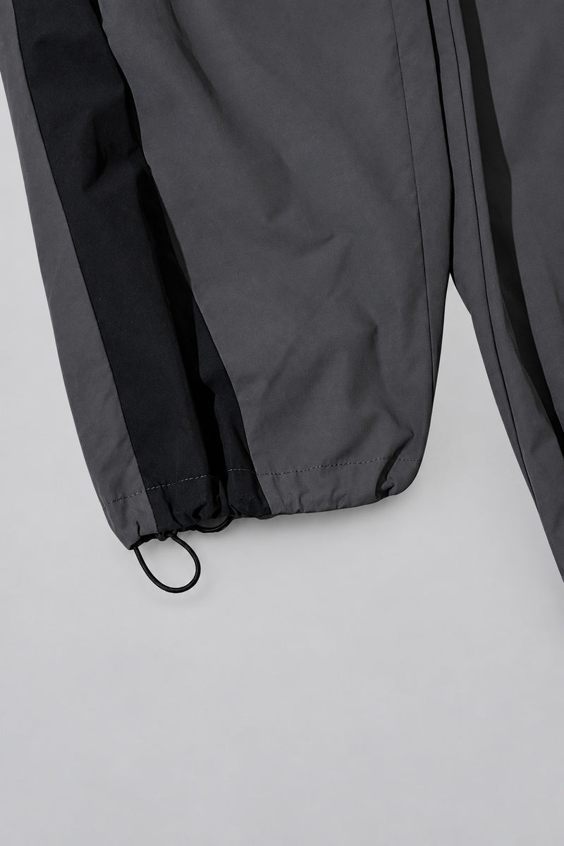 Jogging Y2K édition 'Shadow Sport', détail de l'ourlet réglable, sur fond studio gris clair.