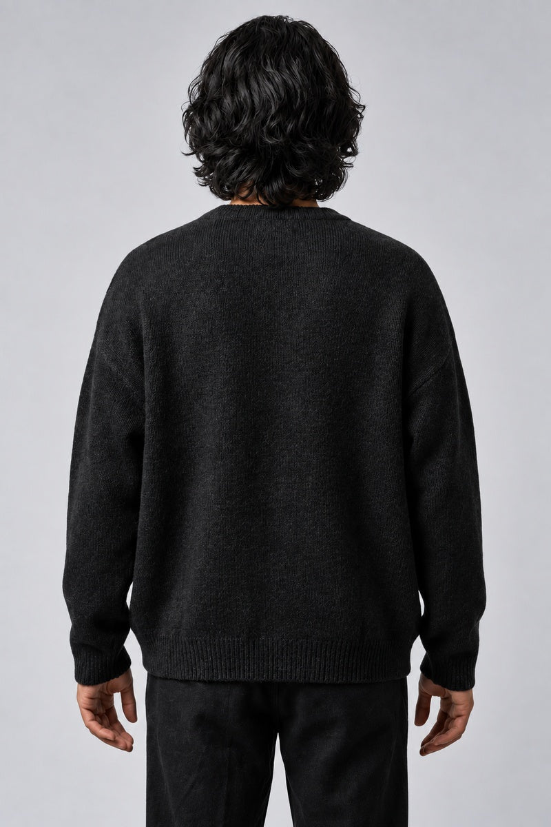 Pull Cosmic noir en maille, porté de dos sur fond gris clair