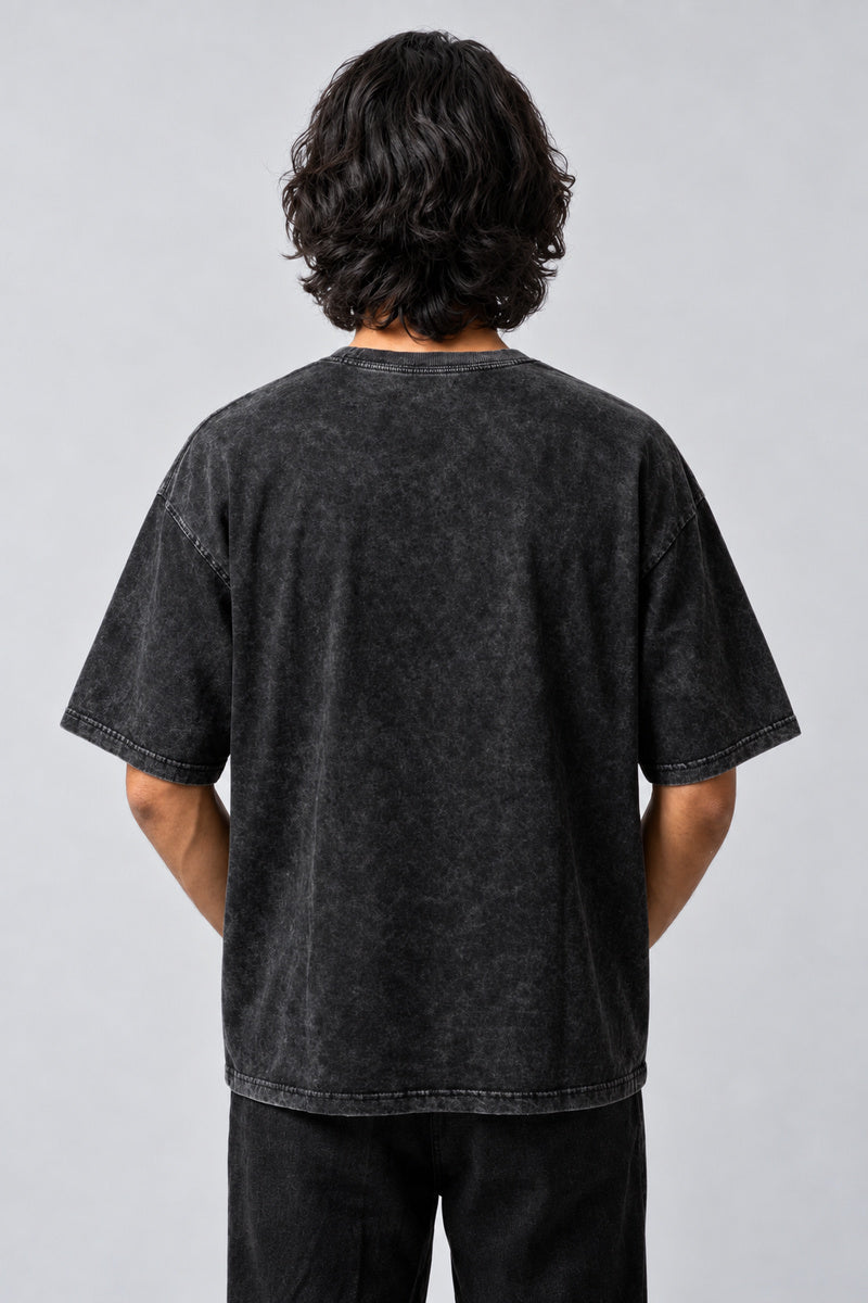 Dos uni du t-shirt oversize gris anthracite délavé, porté sur fond gris perle.