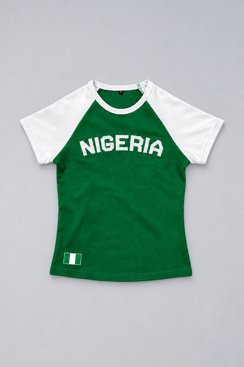 Baby tee Nigeria vert et blanc présenté à plat sur fond gris perle, avec lettrage Nigeria et drapeau.