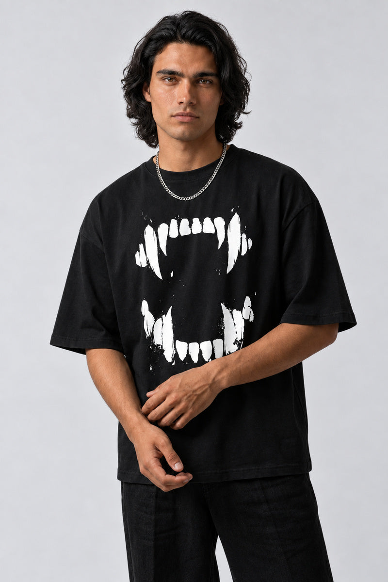 T-shirt noir oversize avec mâchoire et crocs de vampire blancs, porté de face avec une chaîne argentée.