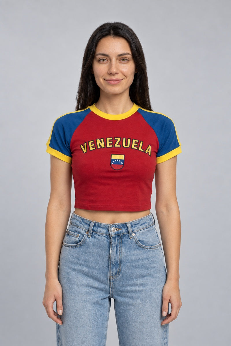 Baby tee Venezuela rouge à manches bleues et bordures jaunes, avec lettrage et écusson, porté de face.